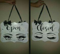 two signs that say open closed and closed with eyelashes hanging from the side of each sign