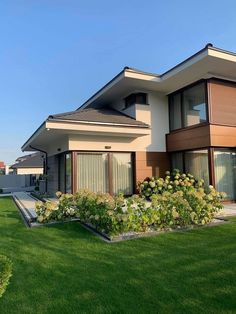 a large house sitting in the middle of a lush green field with lots of flowers