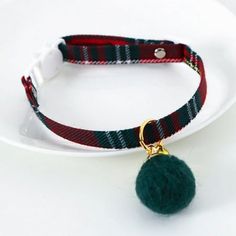 a white plate with a green pom - pom on it and a red plaid collar