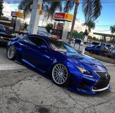 a blue sports car parked in front of a gas station