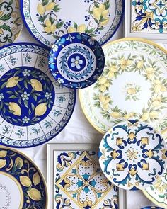 many plates with designs on them are arranged in a row and one is blue, the other has yellow flowers