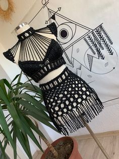 a black and white dress hanging on a wall next to a potted palm tree