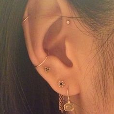 a close up of a person's ear with three different piercings on it