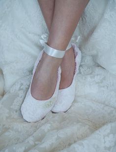 a close up of a person's feet wearing white shoes with bows on them