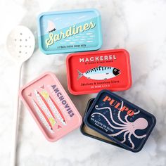 three tins with different types of food in them on a marble counter top next to utensils