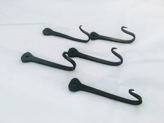 three black hooks are sitting on a white sheet