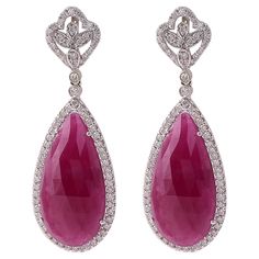 18 Karat White Gold 22.78 Carat Ruby and Diamond Drop Earrings This magnificent merlot red ruby and diamond long slice hanging earring is beautiful. The solitaire pear shaped faceted slice ruby is surrounded with a single cluster of pave set round diamonds in solid white gold, making the look more elegant. The leveled down diamond cluster brings the focus back on the ruby, as the diamonds flash through the light drawing everyone’s eyes to the earring pair. The top part of the earring consists of Pear-shaped Ruby Gemstone Earrings, Formal Pear-shaped Ruby Jewelry, Pear-shaped Ruby Earrings, Ruby Teardrop Earrings Fine Jewelry, Ruby Teardrop Earrings For Formal Occasions, Elegant Pear-shaped Ruby Jewelry, Light Drawing, Hanging Earring, Hanging Earrings