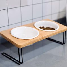 two white bowls with food in them sit on a wooden table next to a toilet