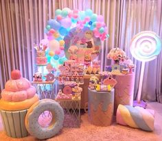 a dessert table filled with lots of cupcakes and balloons