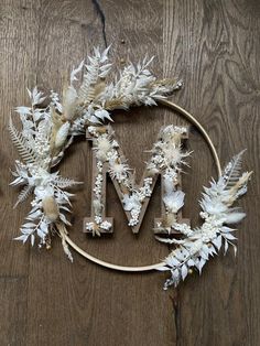 the word mm is made out of white flowers and feathers on a wooden table top