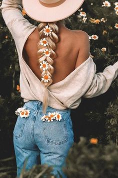 a woman with long hair wearing a cowboy hat and flowered braid in her hair