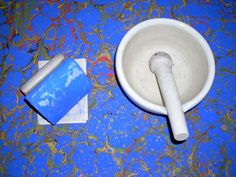 a blue and white bowl sitting on top of a table next to a roll of toilet paper