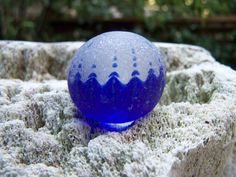 a blue glass ball sitting on top of a rock