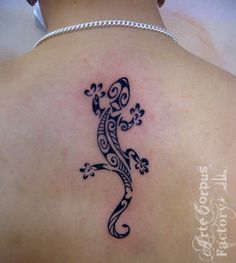 a lizard tattoo on the back of a woman's shoulder