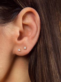 a woman's ear with three small diamond studs