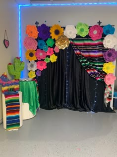 a decorated stage with colorful flowers on the curtain and table cloths in front of it