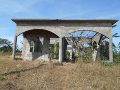 an abandoned building sitting on top of a dry grass covered field