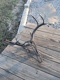 an antelope sculpture sitting on top of a wooden deck next to grass and rocks