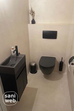 a black toilet sitting next to a sink in a bathroom