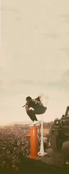 a person jumping over an orange object on top of a car in front of a crowd