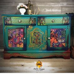 an ornate painted sideboard with flowers on the doors and drawers is displayed in front of a wood paneled wall