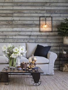 a living room with white furniture and wood paneling on the wall behind it is a coffee table