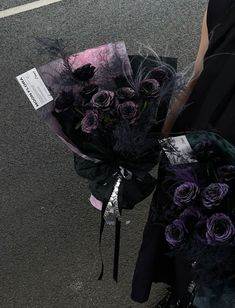 a bouquet of purple flowers sitting on the ground next to a woman's leg