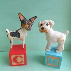 two figurines of dogs standing on blocks with the letter d and m painted on them