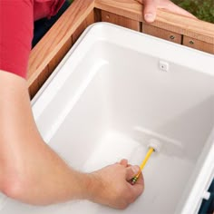 a person is holding a pencil in their left hand and pointing to the bottom of an empty tub