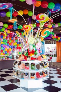 an assortment of candies on display in front of balloons hanging from the ceiling at a candy shop