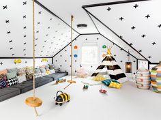 an attic bedroom with black and white stars painted on the walls, a swing bed, and colorful pillows