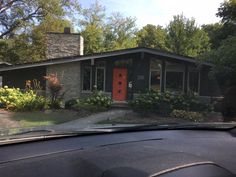 a red door sits in the front yard of a house with trees and bushes around it