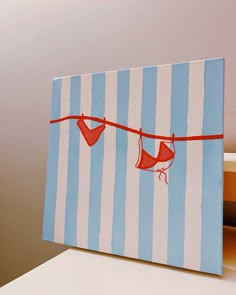 a card with two red hearts hanging from a line on a blue and white striped background