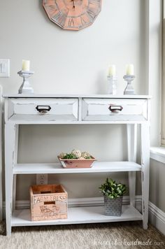 a white table with two drawers and a clock on the wall