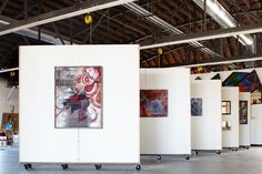 an empty room with paintings on the walls and flooring in front of white partitions