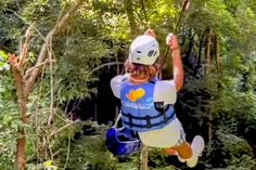 a young man is zipping through the trees on a rope course in the jungle