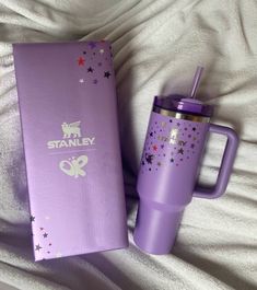 a purple starbucks cup sitting next to a box on top of a white bed sheet