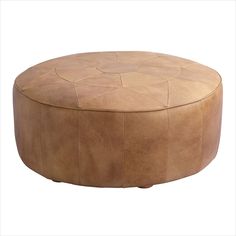 a round leather ottoman sitting on top of a white floor