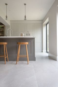 two wooden stools sit in front of an island with marble countertops and white walls