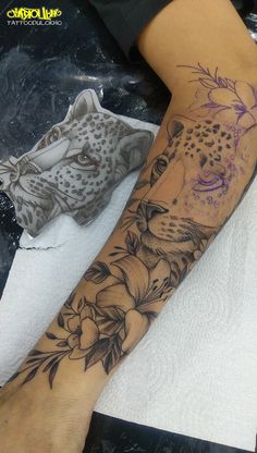 a woman's arm with a tattoo on it that has a leopard and flowers on it