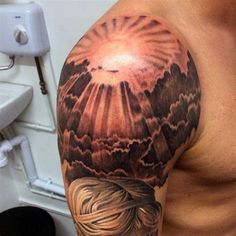 a man's half sleeve with clouds and sun in the sky on his arm