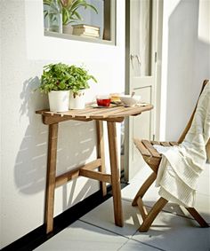 a small table and chair on a porch with a potted plant next to it