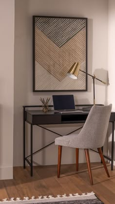 a desk with a laptop on it in front of a wall mounted art work area