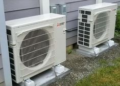 two air conditioners sitting next to each other on the side of a house,