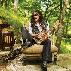 a man sitting in a chair holding an electric guitar