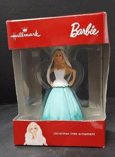 the barbie doll is in its box and it's wearing a blue dress with white trim