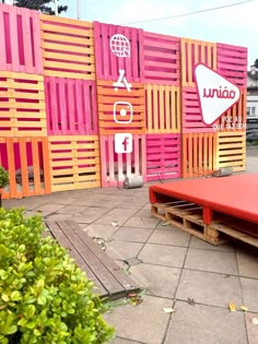 a red bench sitting in front of a pink and orange wall with an upside down sign on it