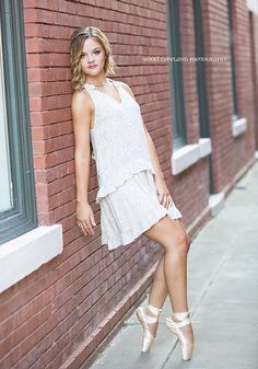 a beautiful young woman leaning against a brick wall