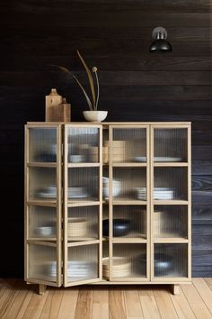 a wooden cabinet with glass doors and plates on it in front of a wood wall