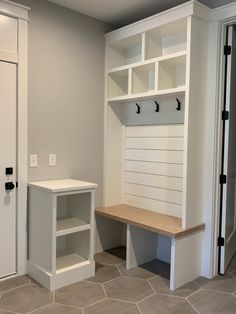 an empty room with some white shelves and a bench in the corner, next to a door